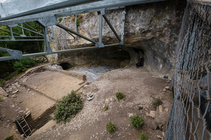 A view from the eyes of a cave behind what appears to be the foundations of a building